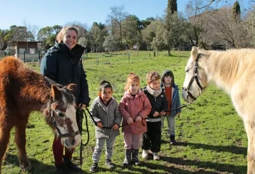 un groupe d'enfants et leur animatrice posent entre deux chevaux