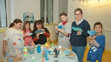 un groupe d'enfants et leurs animatrices montrent des oiseaux en carton