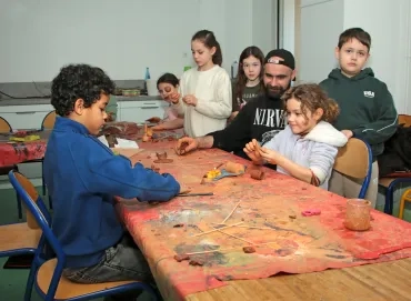 un groupe d'enfants et leur animateur modèlent des morceaux d'argile