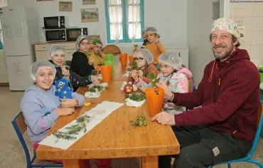un groupe d'enfants et leur animateur posent en cuisine avec des herbes aromatiques