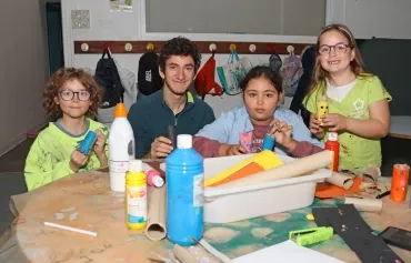 un groupe d'enfants et leur animateur montrent des rouleaux de papier toilette décorés