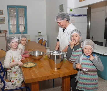 un groupe d'enfants et leur animatrice sont en cuisine en train de lécher leurs doigts