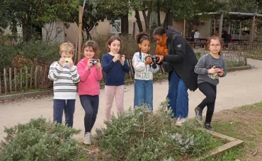 un groupe d'enfants et leur animatrice prennent des photos du romarin
