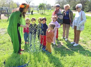 Un groupe d'enfants et leur animatrice déguisée ainsi que trois femmes plus âgées sont devant des fleurs