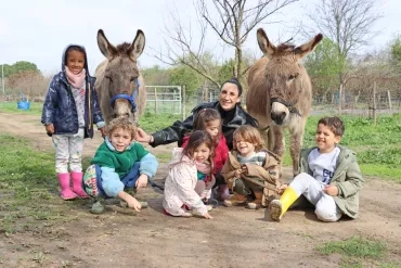 Un groupe d'enfants et leur animatrice posent avec deux ânes