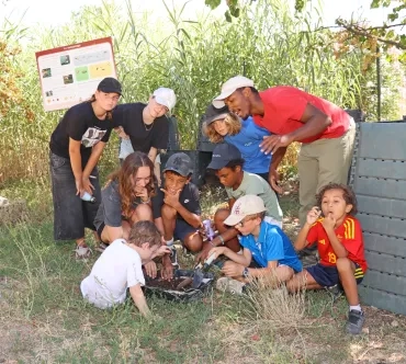 Un groupe d'enfants et leur animateur ont les mains dans la terre