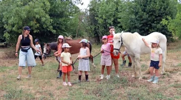 un groupe d'enfants et leurs animatrices posent avec deux chevaux
