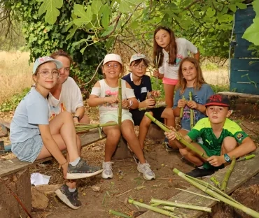 un groupe d'enfants et leur animatrice manipulent des morceaux de canne de Provence