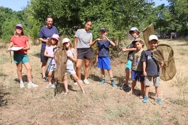 Un groupe d'enfants et leurs animatrices posent avec des filets à papillons