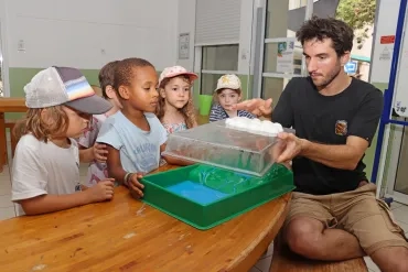 un groupe d'enfants et leur animateur sont autour d'une maquette