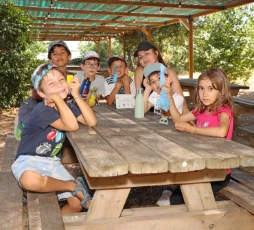 Un groupe d'enfants et leur animatrice montrent des petits sacs colorés