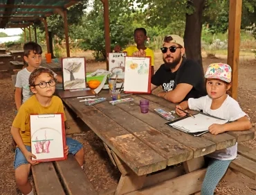 un groupe d'enfants et leur animateur montrent des dessins