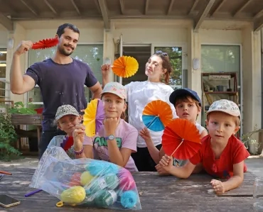 Un groupe d'enfants et leurs animateurs s'éventent avec des papiers pliés