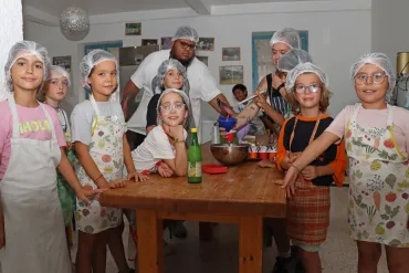 un groupe d'enfants et leurs animateurs remplissent des pots en cuisine