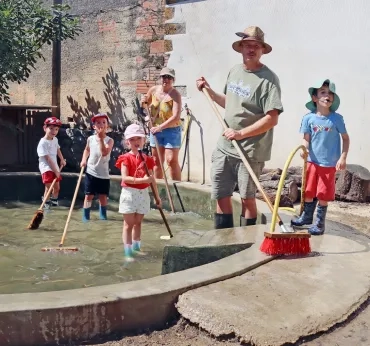 Un groupe d'enfants et leurs animateurs frottent le sol avec des balais