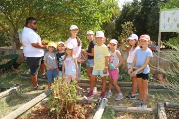un groupe d'enfants et leur animateur posent dans un jardin