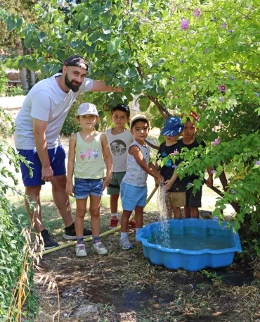 Un groupe d'enfants et leur animateur remplissent une bassine