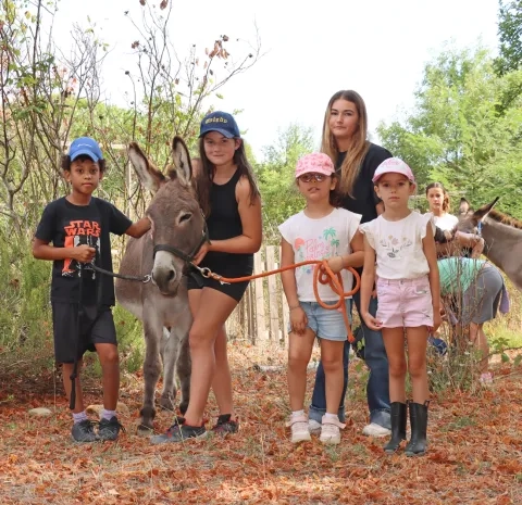 Un groupe d'enfants et leur animatrice posent avec un âne