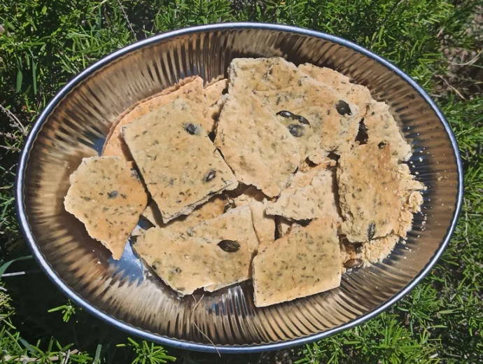Des crackers dans un plat sont disposés sur du romarin
