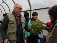 Un animateur propose à sentir un plant de sauge ananas à un groupe d'adultes