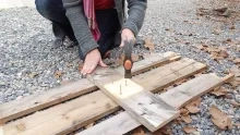 une personne enlève les clous d'une palette grâce à un marteau