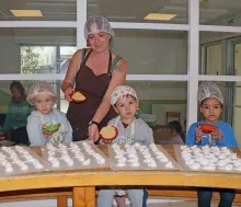 Un groupe d'enfants et leur animatrice sont en cuisine montrent leur réalisations