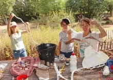deux enfants et leur animatrice montrent des morceaux de bois décorés