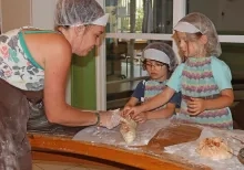 Deux enfants et une animatrice façonnent du pain
