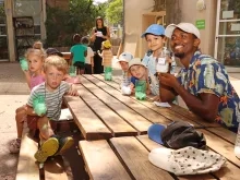 un groupe d'enfants et leur animateur montrent des bas de bouteilles en plastique