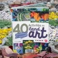 Le livre 40 activités de land art est exposé entouré d'une oeuvre de land art composée de pierres, de branchages, de fleurs et feuilles