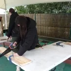 3 adultes scient des planchent de bois