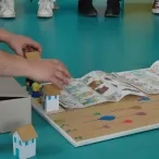 Une personne assise par terre présente un jeu de plateau fait main