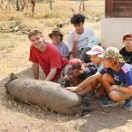 Un groupe d'enfants et leurs animateurs caresssent un cochon couché