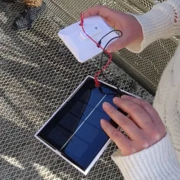 Gros plan sur un petit panneau photovoltaïque relié à une petite ampoule allumée