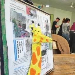 tableau d'une girafe en boite d'oeuf avec en fond les participants à la formation